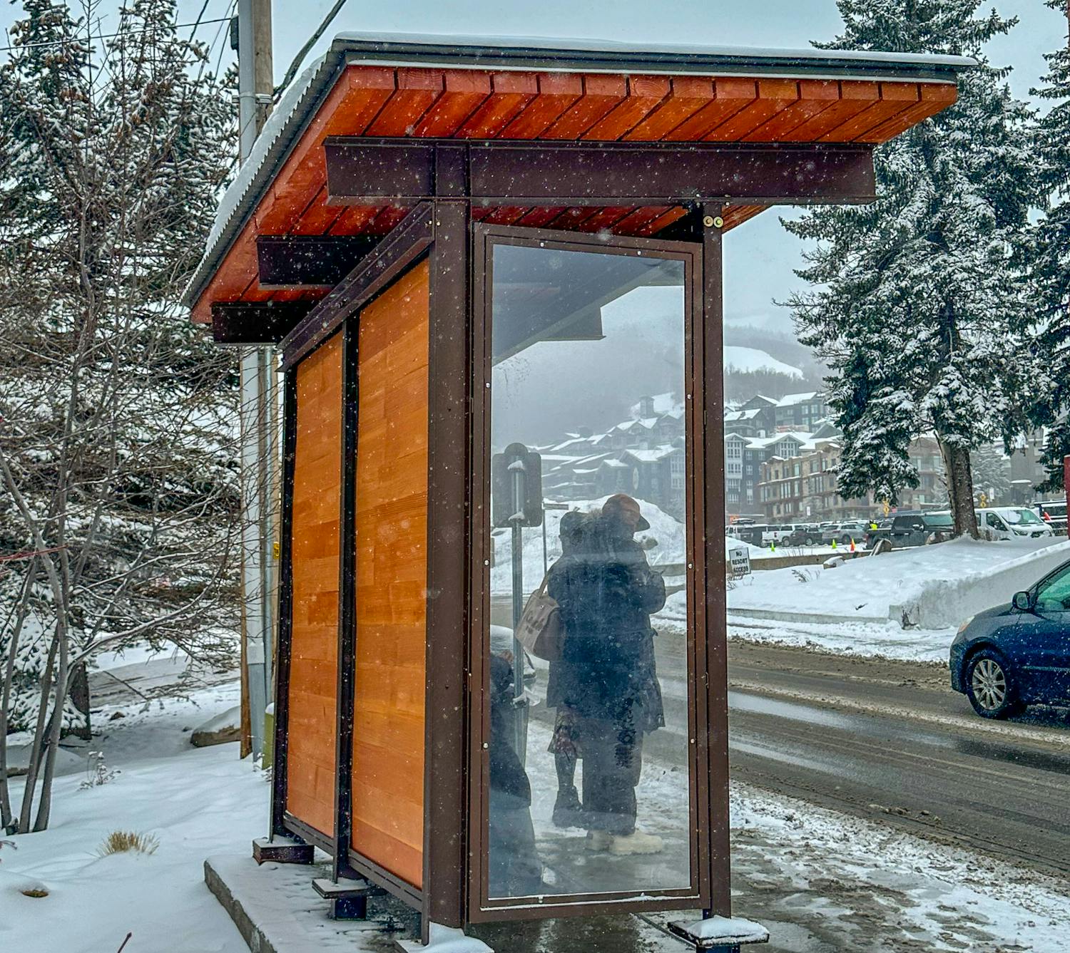 Riders stand under a MODSTREET Modular Bus Shelter waiting for a bus.