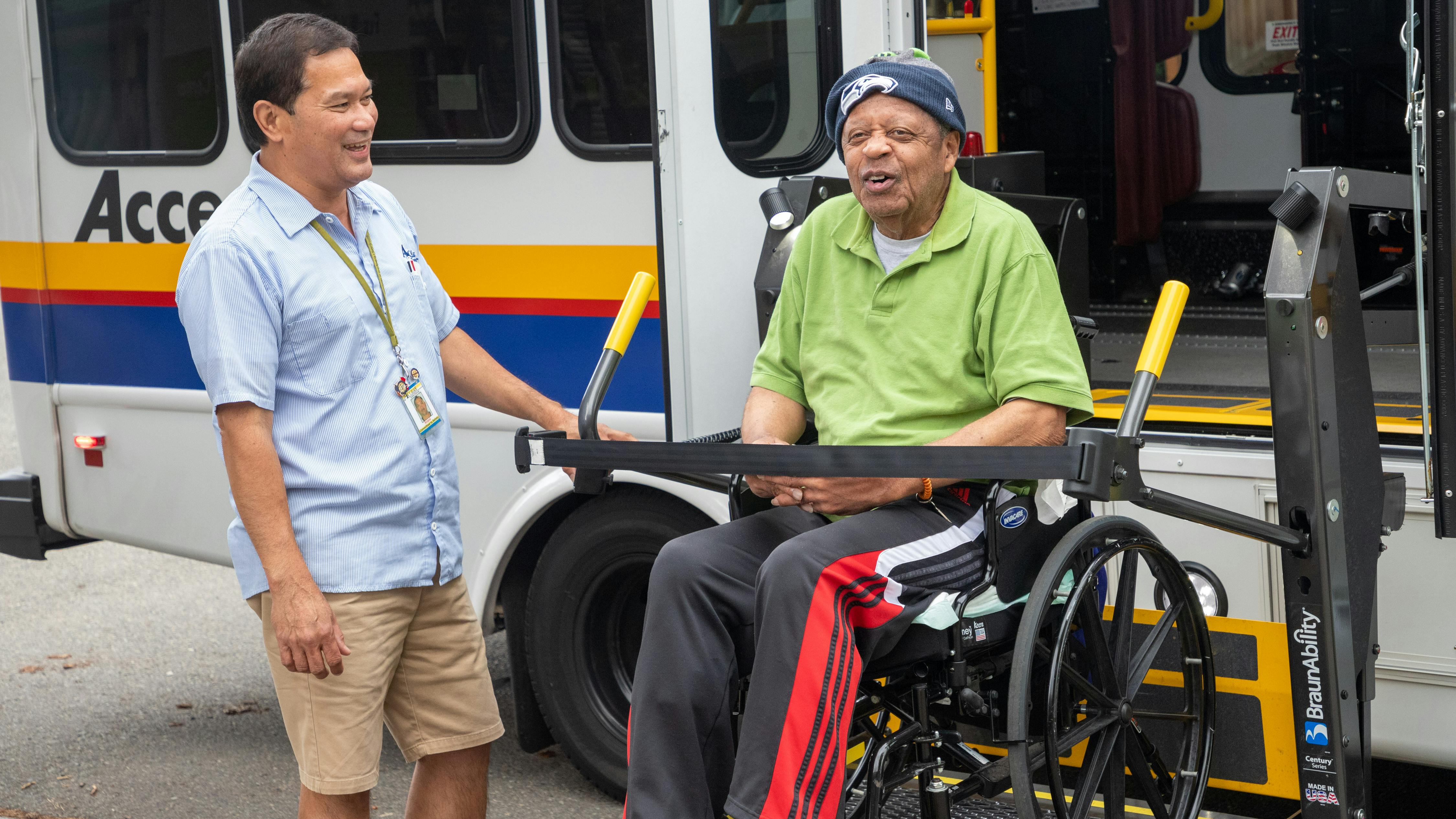 An operator helps a wheelchair users off an accessible bus.