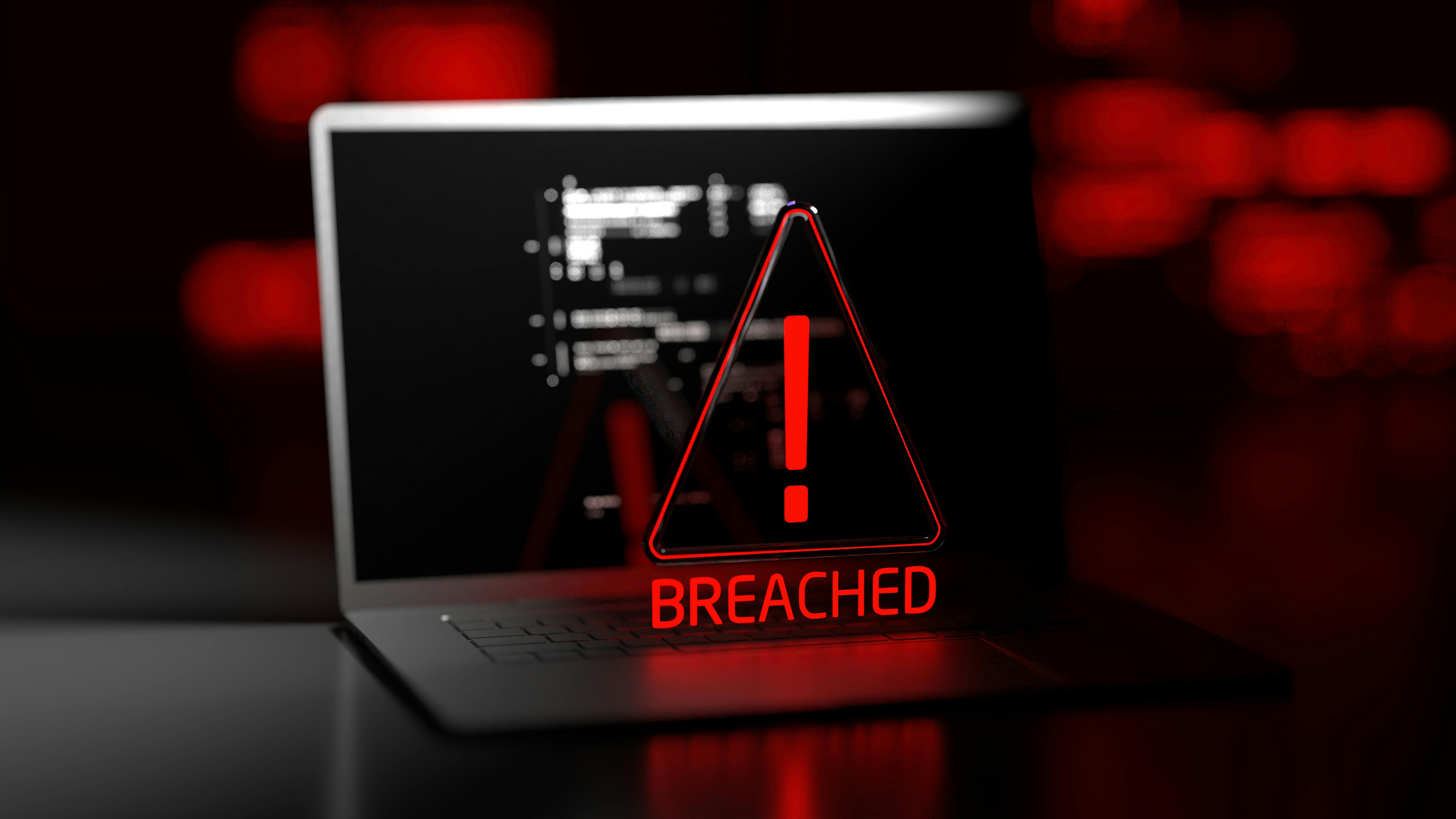 The image displays a rendering of a computer with a triangular icon with an exclamation mark in it in front, with 'BREACHED' written below it.