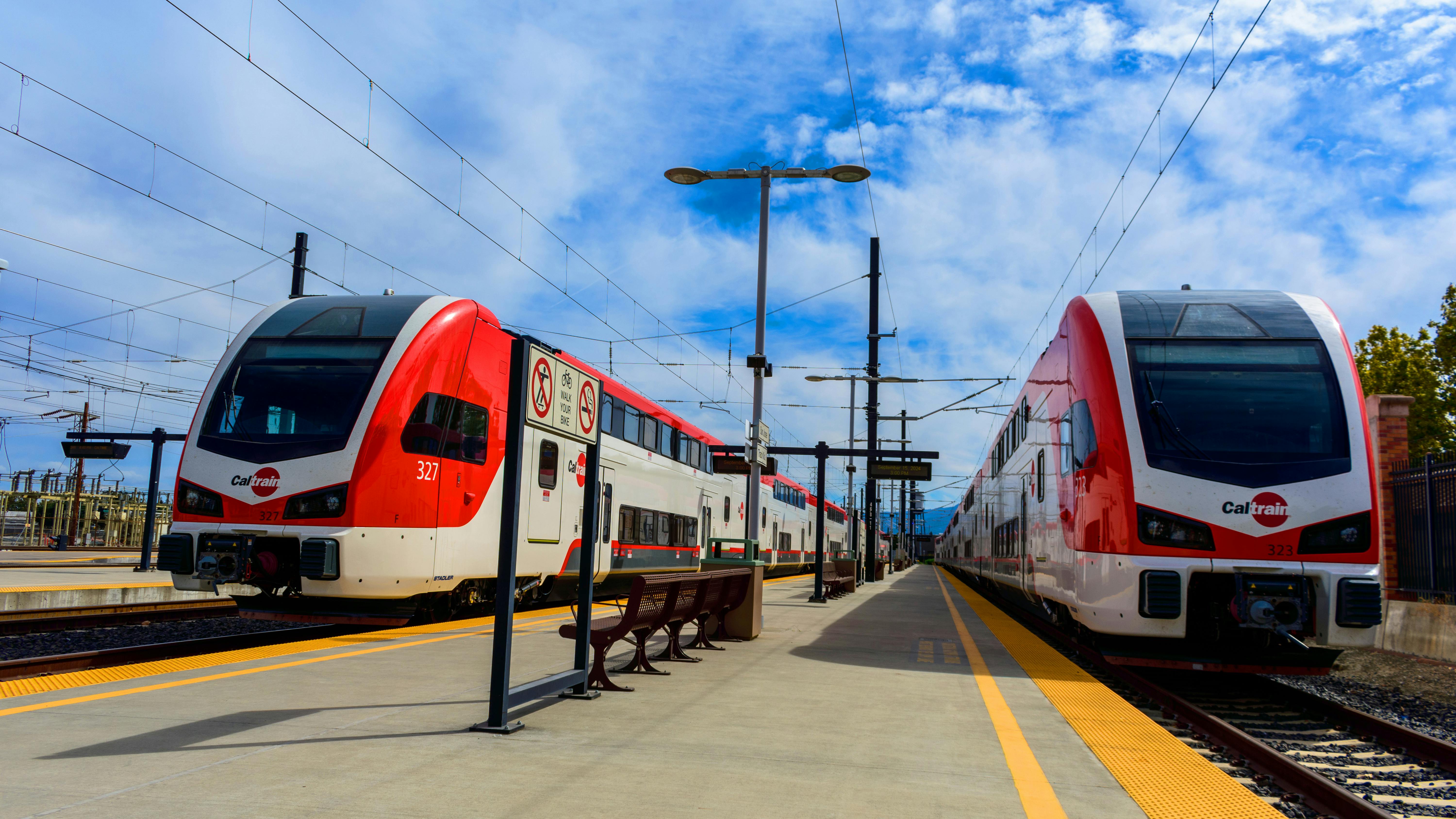 A pair of electric Caltrain trains sit at a station.