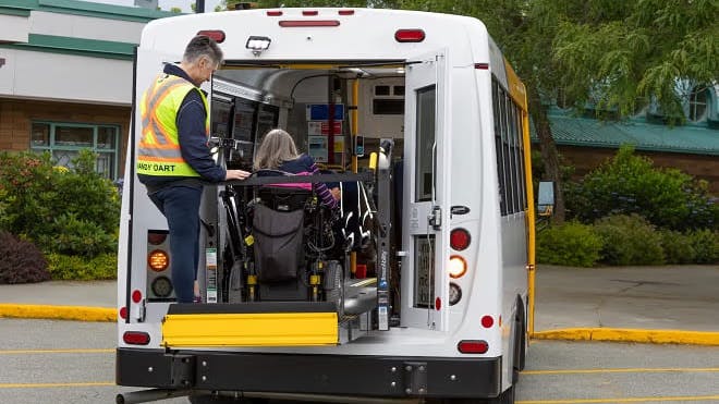 A HandyDART operator assists a rider entering into a vehicles.