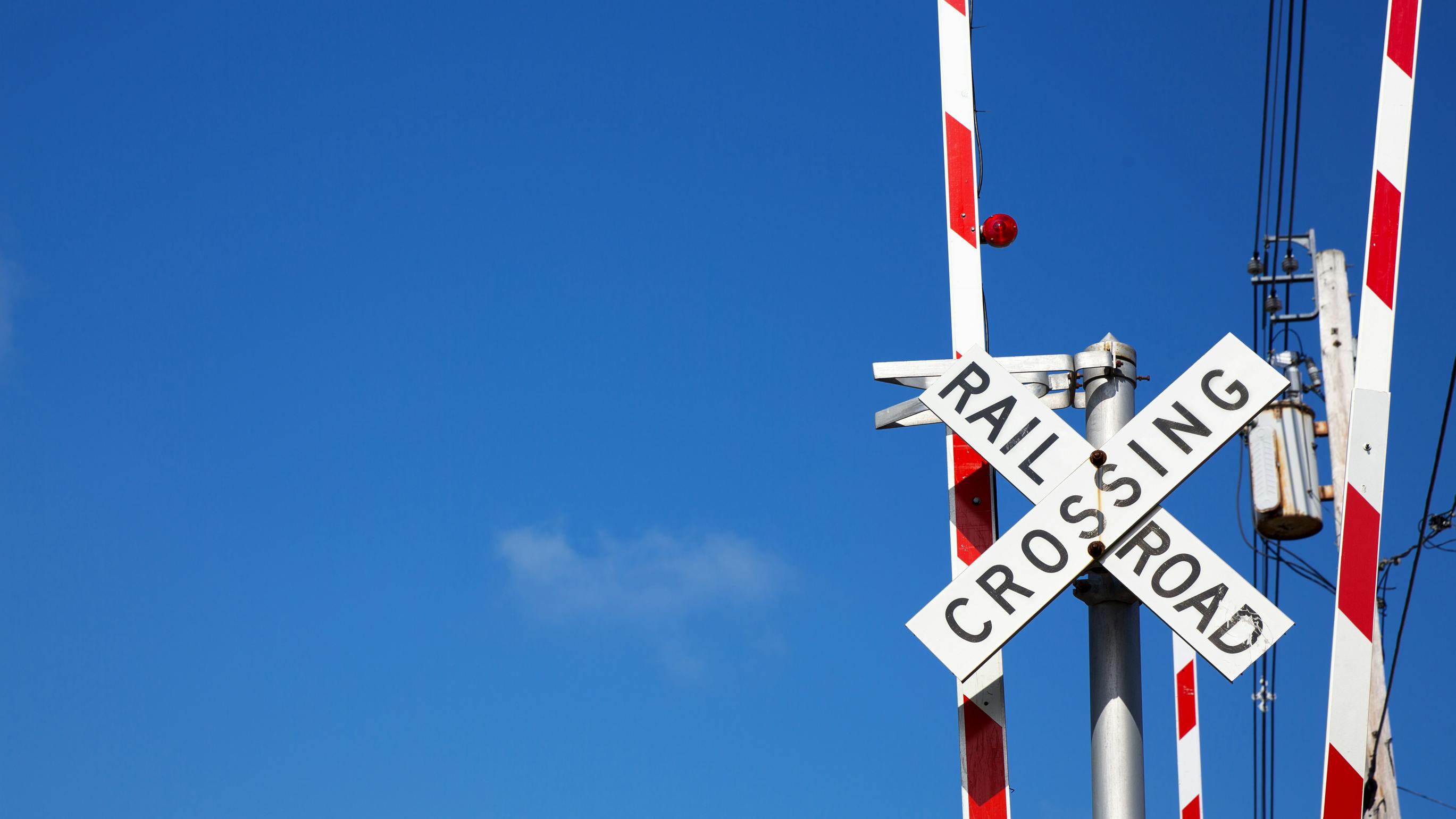 Railroad crossing sign against blue sky background.