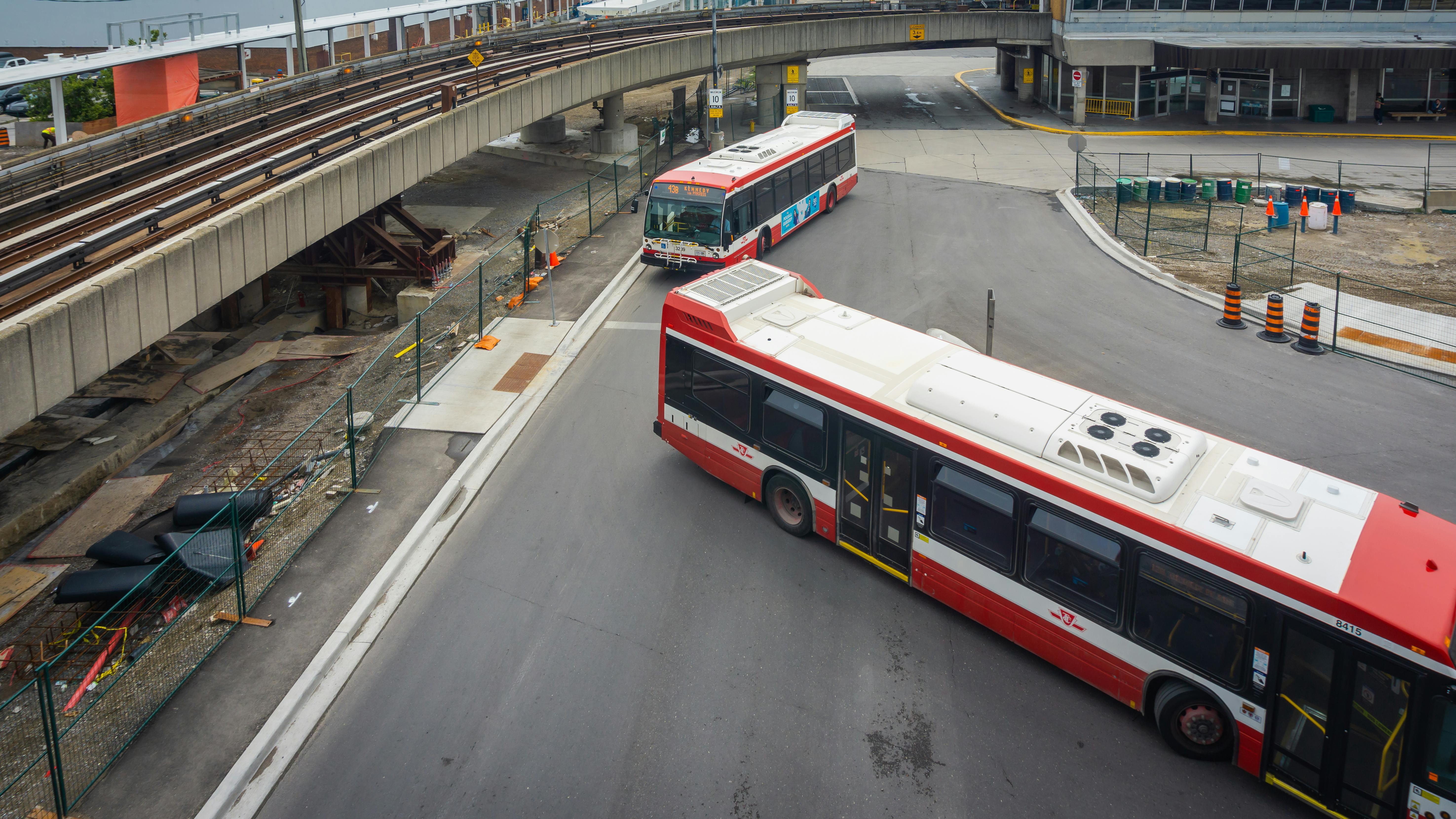 The image shows two TTC buses entering a transit center.