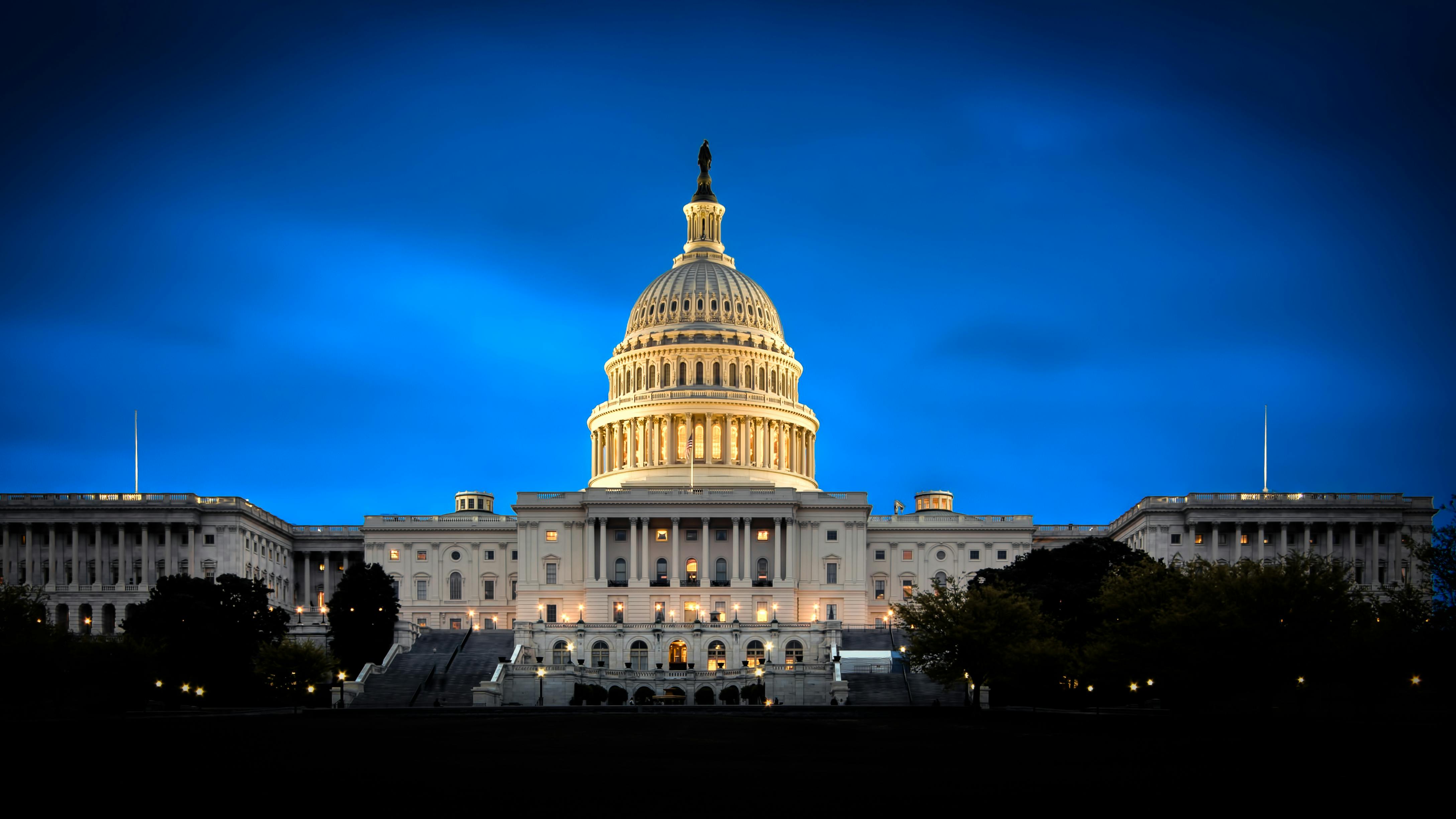 The image shows a wide shot of the US Capitol at night.