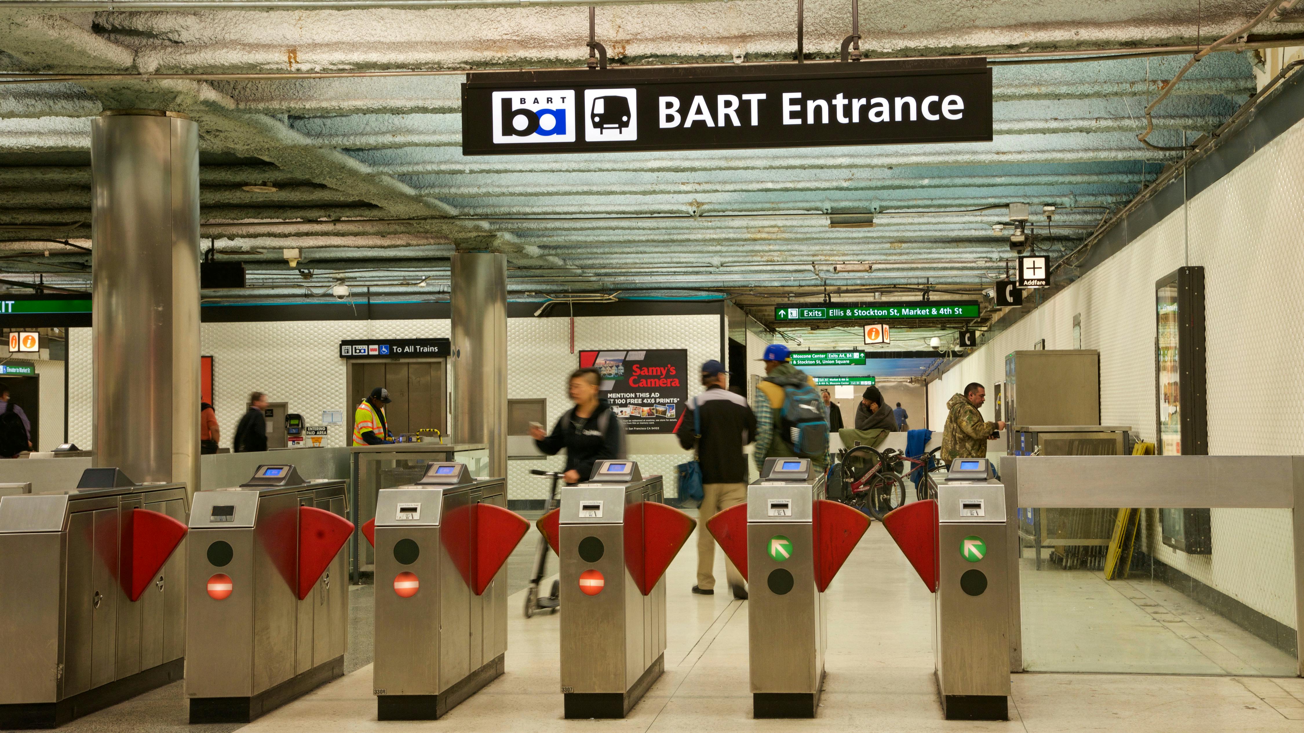 Entrance fare gates to Powell Street BART Station with people in station