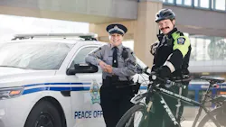Transit peace officers stand posed in front of a patrol car and bike. Transit peace officers stand posed in front of a patrol car and bike.