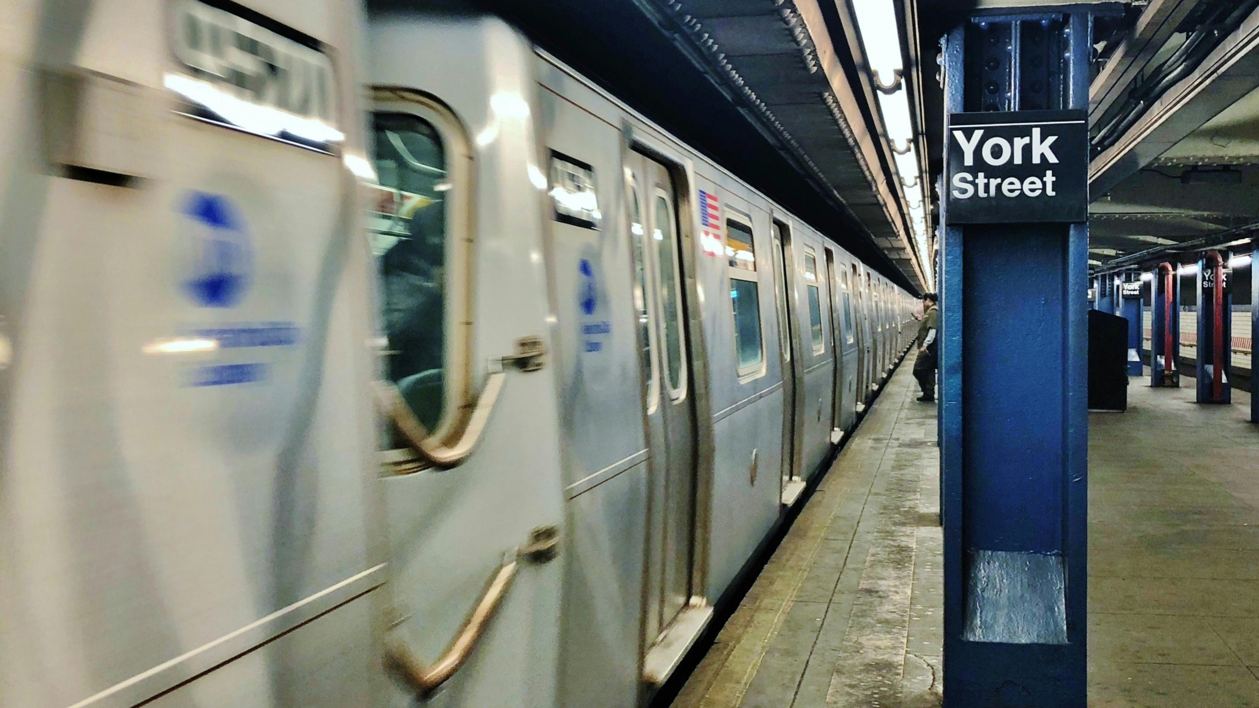 An MTA subway car passes by in a blurred photo.