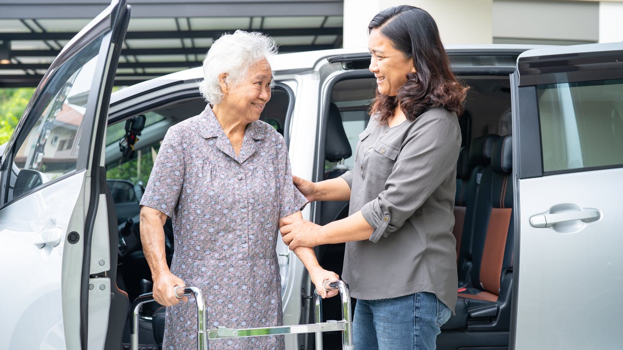 A SilverRide operator aids a passenger exiting a van.