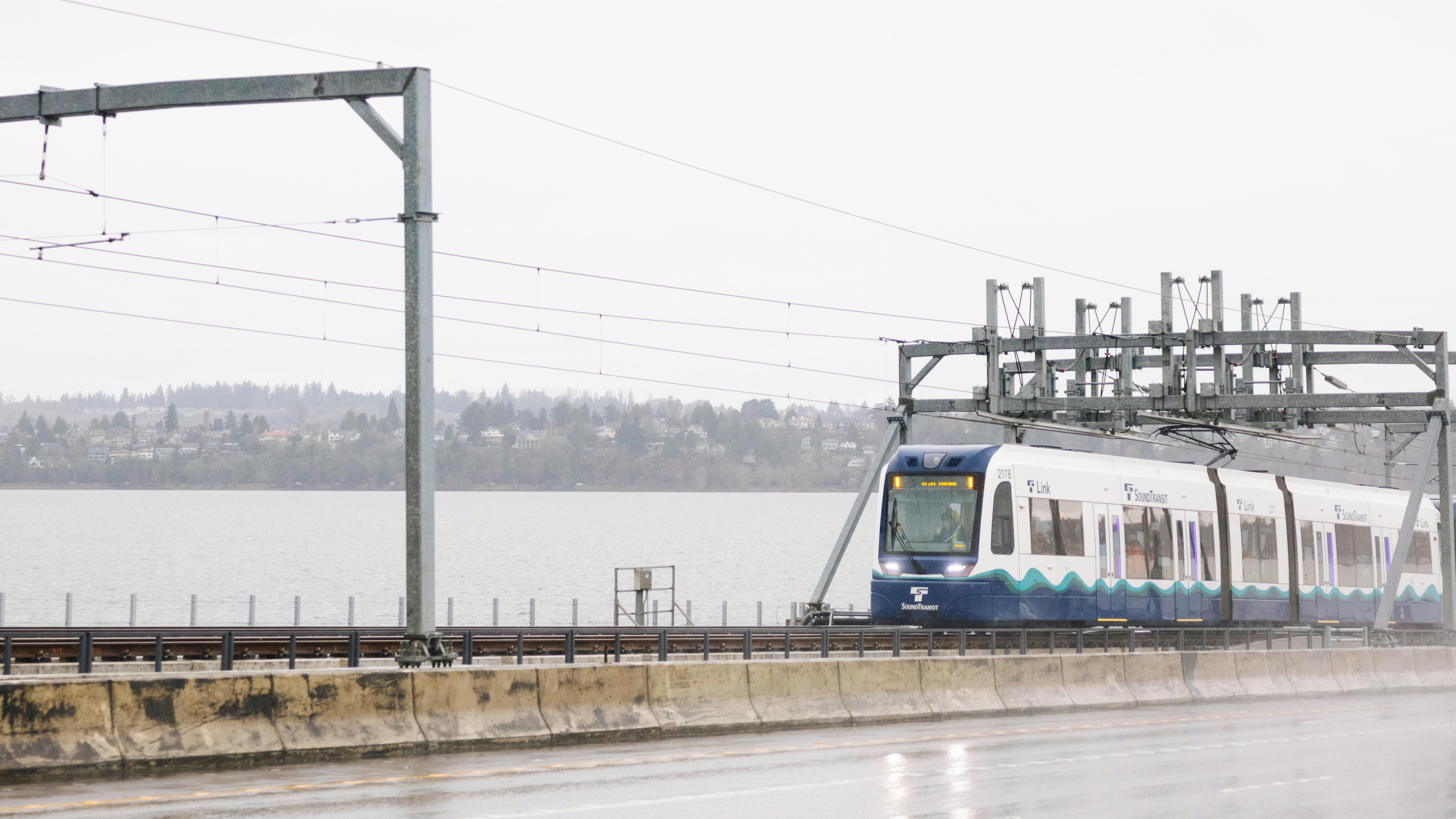 A Sound Transit light-rail vehicle crosses water on a floating bridge.