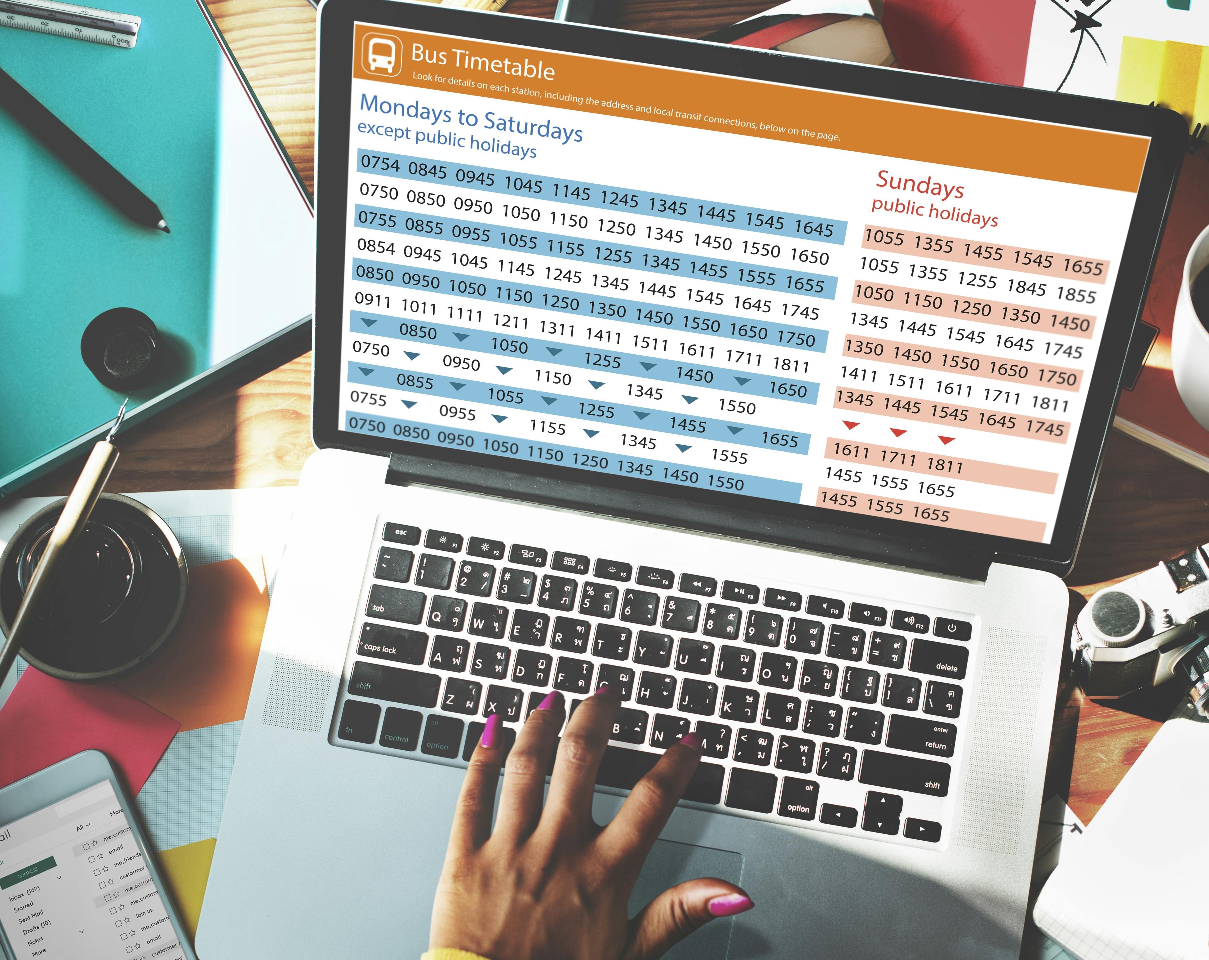 hand typing on laptop with screen that shows bus schedule time table