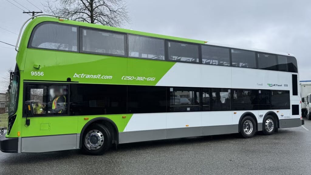 The image shows the side profile of one of the new double decker buses wrapped in green livery.