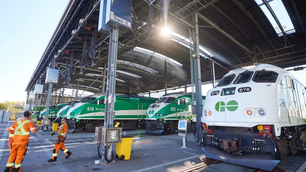 Workers in high-vis gear speak outside of GO Express trains.