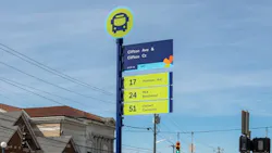 A Cincinnati Metro bus stop sign on a blue pole at the intersection of Clifton Avenue and Clifton Court. The sign displays stop ID 4605 and lists three routes: Route 17 Hamilton Ave, Route 24 MLK Beechmont, and Route 51 Uptown Connector, each on a yellow-green panel. A circular topper features a navy bus icon on a yellow-green background. The sign is positioned on a sidewalk at a signalized intersection, with a historic brick building, a crosswalk, and parked vehicles visible in the background under a partly cloudy sky. A Cincinnati Metro bus stop sign on a blue pole at the intersection of Clifton Avenue and Clifton Court. The sign displays stop ID 4605 and lists three routes: Route 17 Hamilton Ave, Route 24 MLK Beechmont, and Route 51 Uptown Connector, each on a yellow-green panel. A circular topper features a navy bus icon on a yellow-green background. The sign is positioned on a sidewalk at a signalized intersection, with a historic brick building, a crosswalk, and parked vehicles visible in the background under a partly cloudy sky.