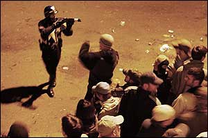 An officer aims a pepper-pellet gun at the crowd celebrating outside Fenway Park, Oct. 21, 2004.
