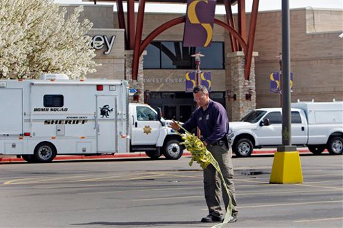 ATF agent Doug Lambert rolls up police crime scene tape at one of the entrances at Southwest Plaza Mall in Littleton, Colo.