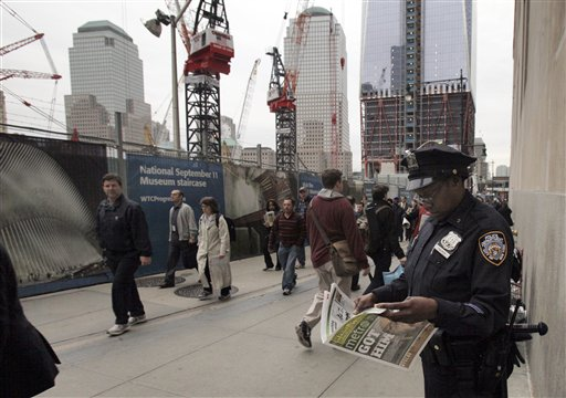A New York City police officer looks at a copy of a newspaper featuring the image of Osama bin Laden, as she works adjacent to Ground Zero.