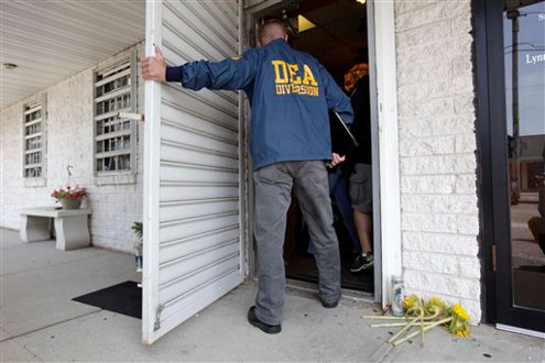 A DEA agent enters the pharmacy where four people were killed in a shooting on June 19.