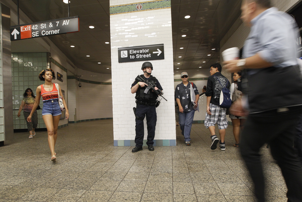 A heavily armed New York City police officer stands guard at a Times Square subway station.