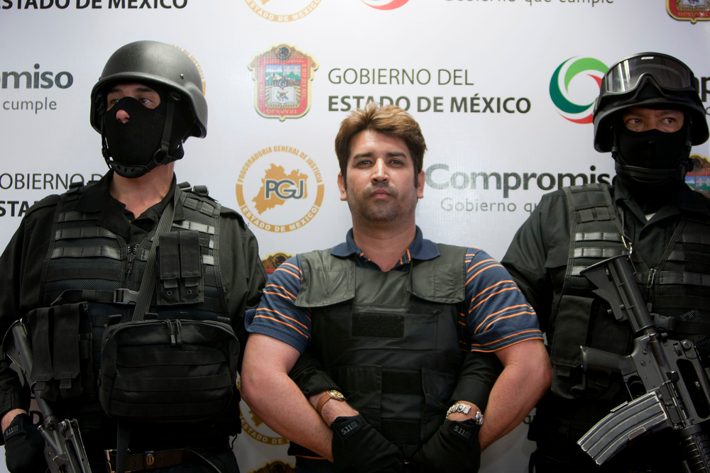 Mexico state policemen escort Oscar Garcia, 36, during a presentation to the press in Toluca.