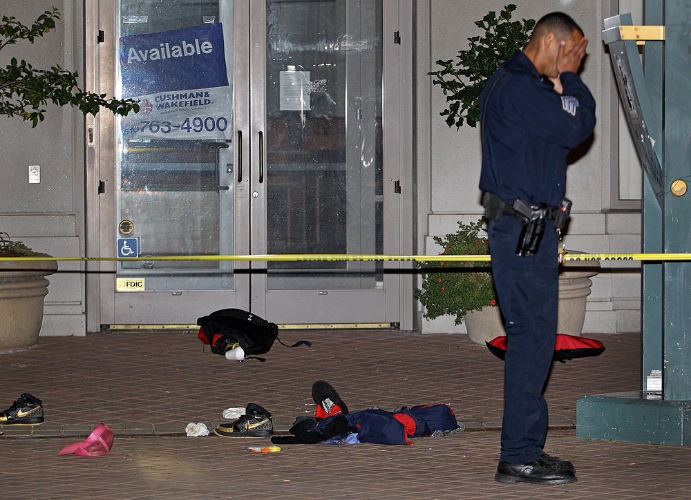 An Oakland police officer raises his hands to his head at the scene where a man was shot and killed near an Occupy Oakland encampment Thursday, Nov. 10, 2011, in Oakland, Calif.