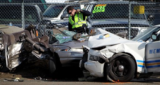 A Memphis police officer inspects the wreckage of a vehicle following a collision involving a fellow officer at the three-way intersection of Crump Blvd, Walnut St. and Georgia Ave. in Memphis, Tenn. Sunday, Aug. 26, 2012. Two people in the private car were killed, while two others were rushed to the Regional Medical Center at Memphis in extremely critical condition. The officer was also injured, although not as seriously. Witnesses said the officer was driving at high speed without his lights or siren on.