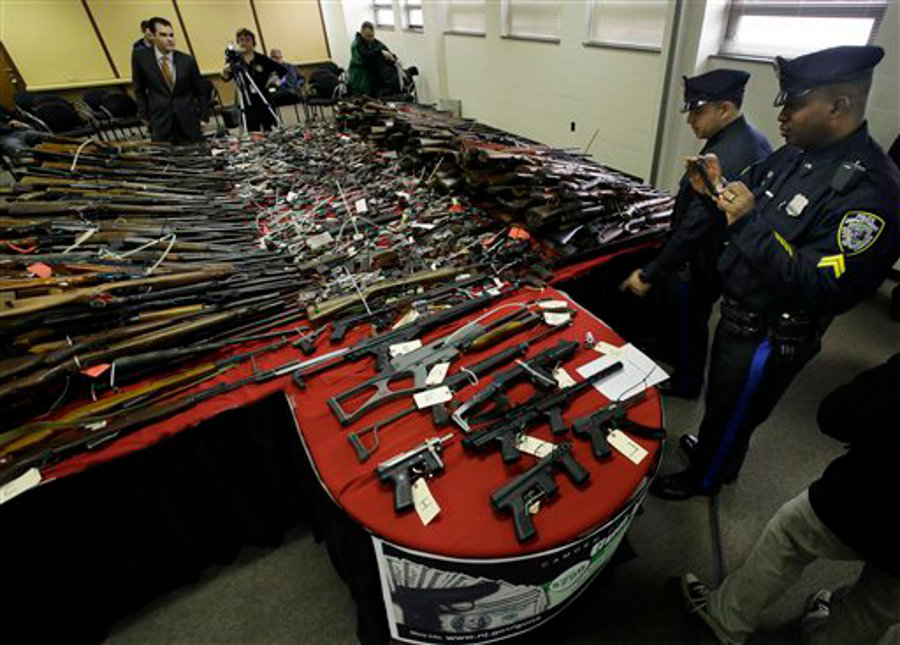 Camden police officers exaime guns displayed on tables at police headquarters in Camden, N.J. on Dec. 18.