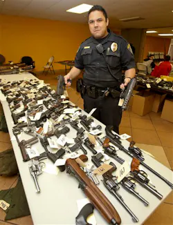 San Diego Police Officer Jonathan Bamba holds a fully automatic tech 9 and a tech 22 at the gun exchange held on Dec. 21. San Diego Police Officer Jonathan Bamba holds a fully automatic tech 9 and a tech 22 at the gun exchange held on Dec. 21.