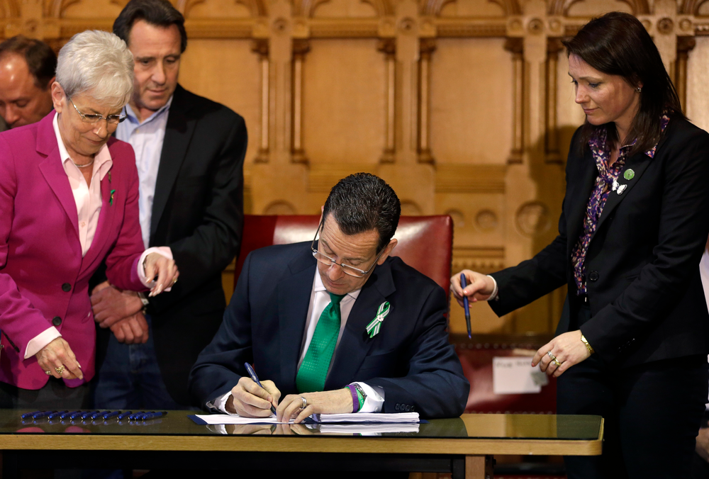 Connecticut Gov. Dannel P. Malloy, center, signs legislation at the Capitol in Hartford, Conn. on April 4.