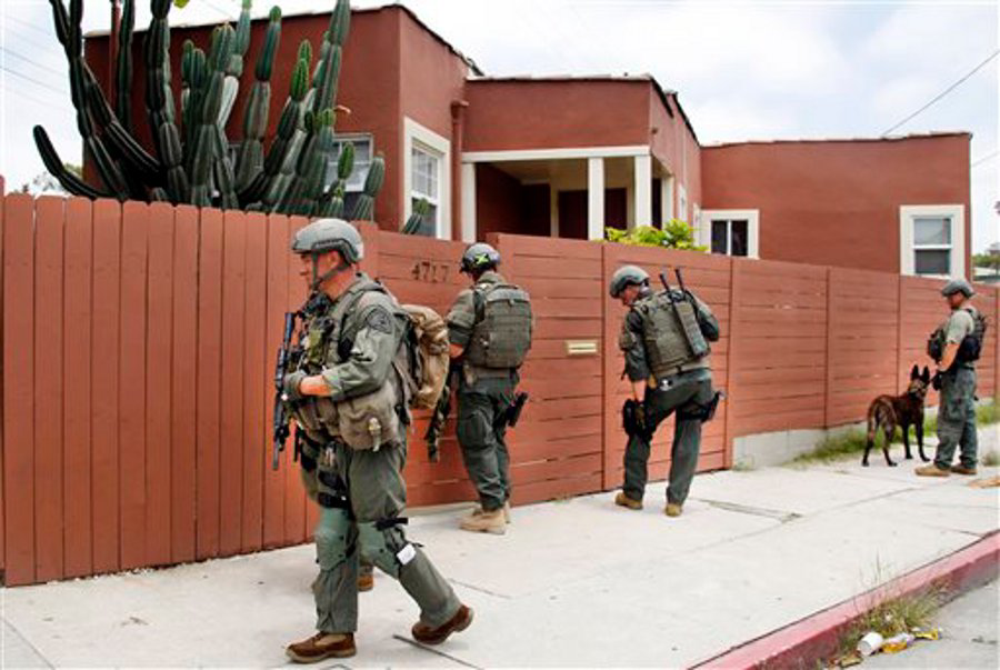Los Angeles Sheriff's deputies search a city street for suspects after two police officers were shot and wounded in an attack outside a police station in the Mid-City area of Los Angeles on June 25.