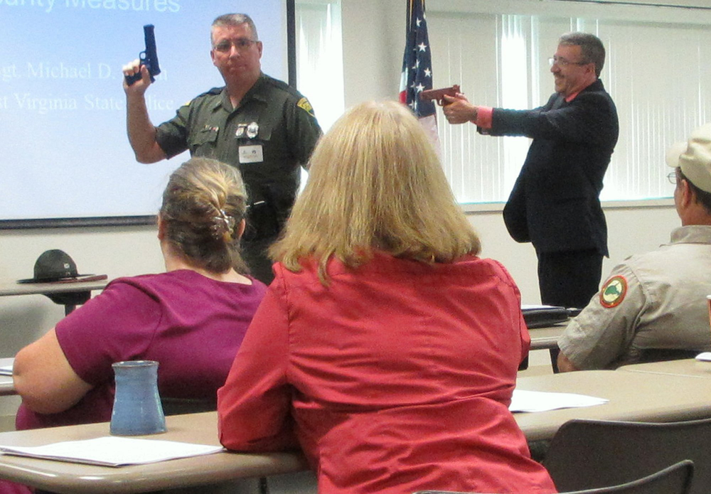 John L. Fernatt, right, of West Virginia's Bureau of Risk and Insurance Management surprises Sgt. Michael Lynch of the state police, left, with a fake weapon during a workshop for civilian office workers on how to survive a mass shooting in the workplace on May 30, in Charleston, W.Va.