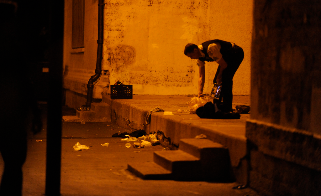 A Chicago police officer picks through debris at the crime scene where a number of people were shot, including a 3-year-old child, in a city park on Sept. 19.