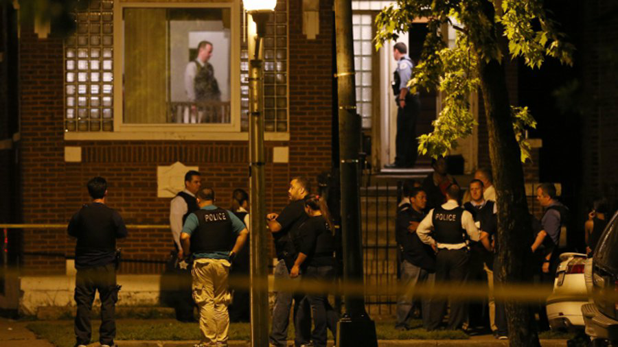 Chicago officers and detectives gather at the home where 11-year-old Shamiya Adams was shot Friday night.