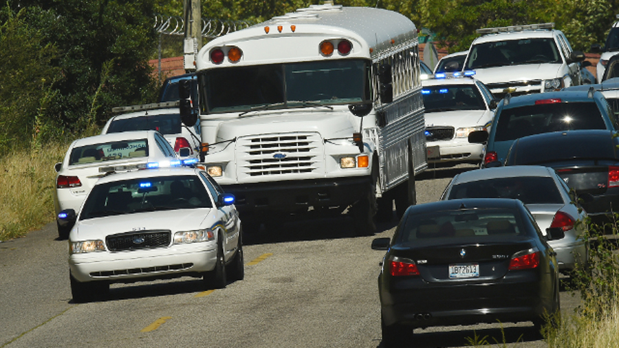 Police officers escort UPS employees on a bus from the scene where three people were killed, including the gunman, at a UPS facility in Birmingham, Ala. on Sept. 23.