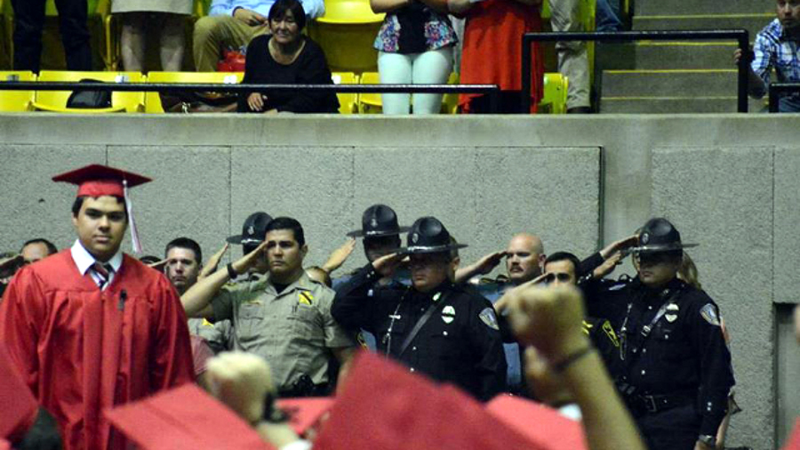 As Dakota, the son of Deputy Sonny Smith, walks across the stage, a group of officers salutes him.