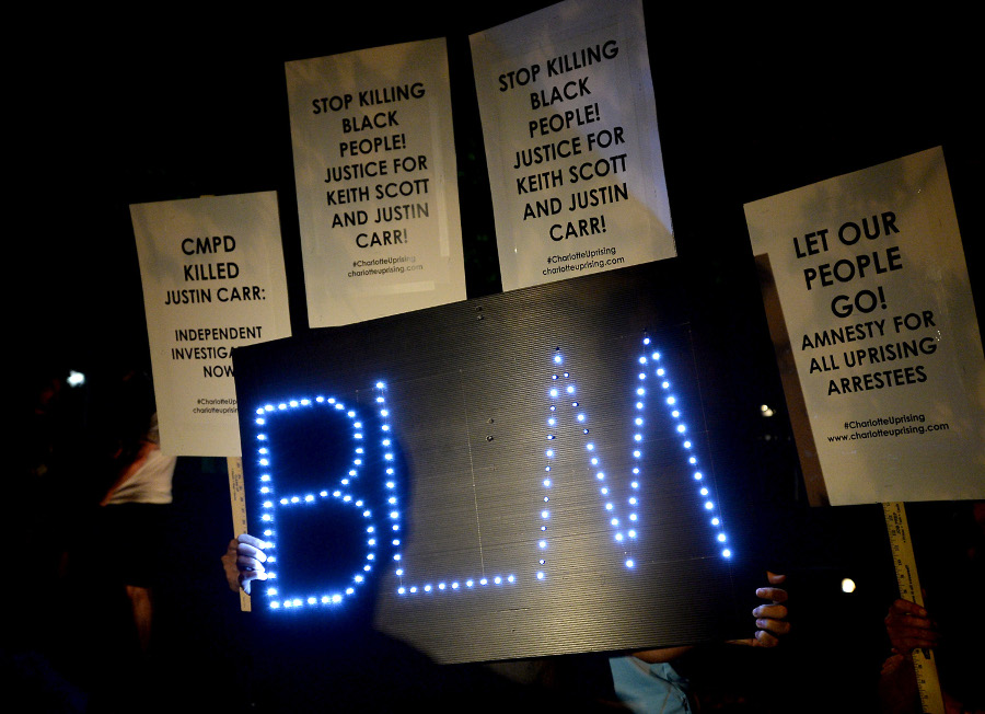 Protesters hold signs during a gathering outside Jail Central in uptown Charlotte on Sept. 30.