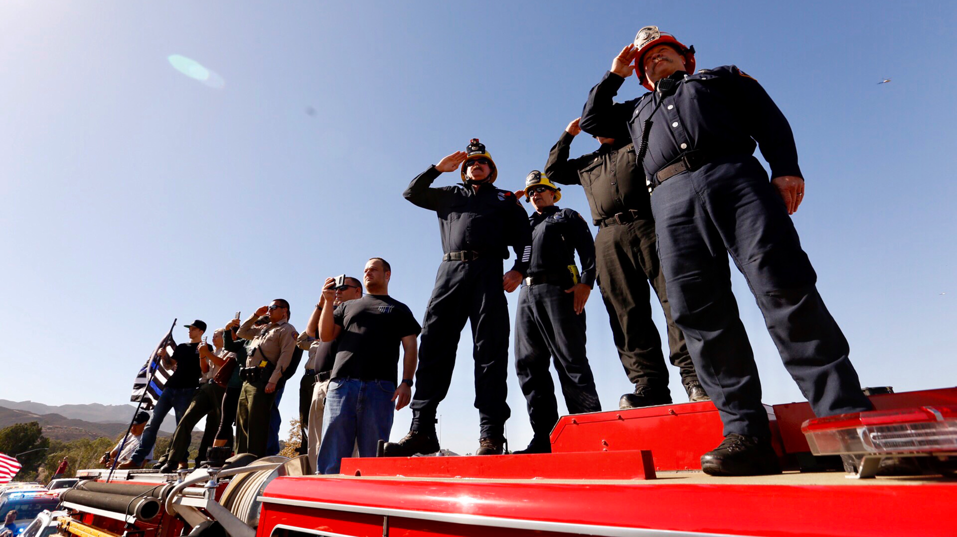 Firefighters salute the procession as the hearse carrying the casket of Ventura County Sheriff Sgt. Ron Helus, who was killed yesterday in the Thousand Oaks mass shooting, as it heads north on the 101 Freeway headed to Ventura.