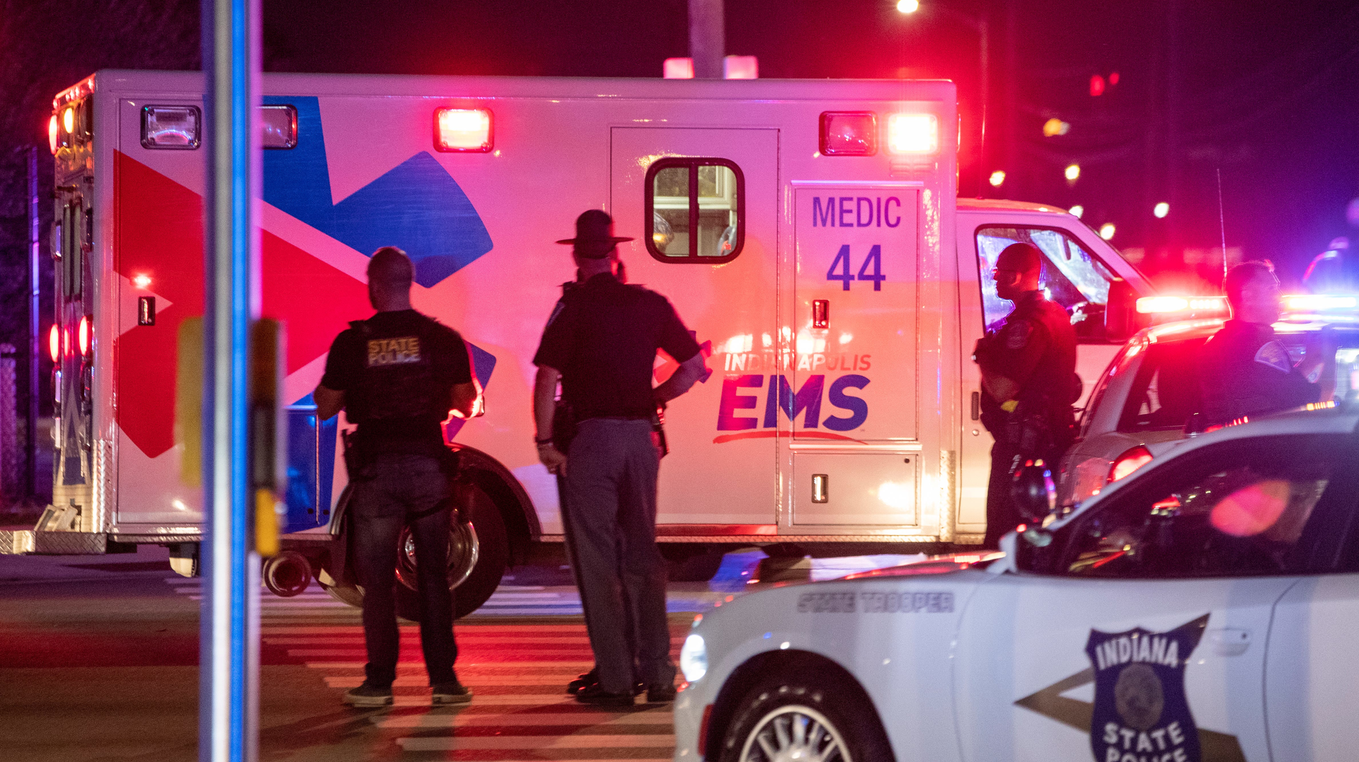 An ambulance drives toward a hospital Wednesday at the scene of a shooting that reportedly wounded an Indianapolis police and critically injured a woman and girl.