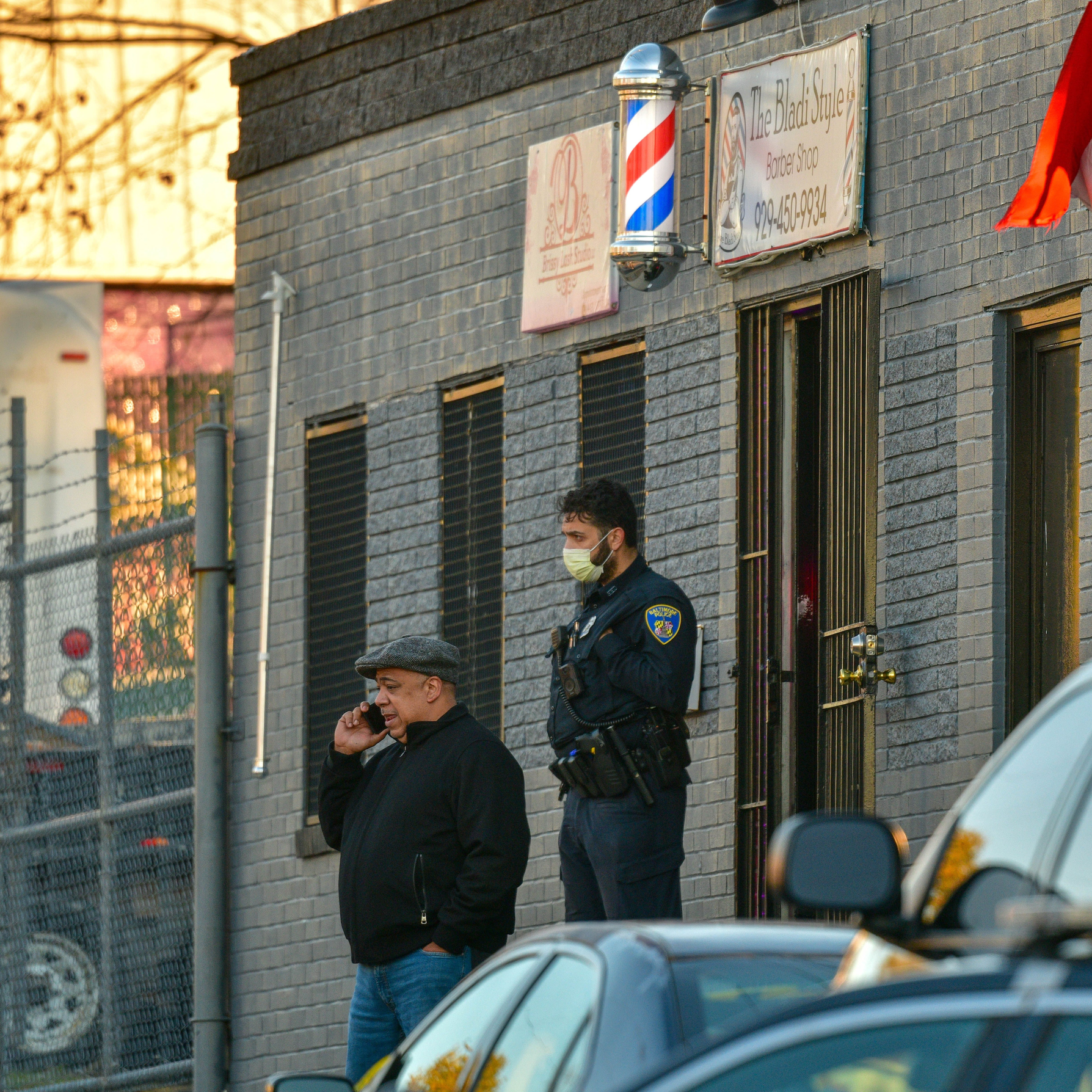 Baltimore Police Commissioner Michael Harrison talks on a phone outside an East Baltimore barbershop following a fatal shooting involving an off-duty officer.