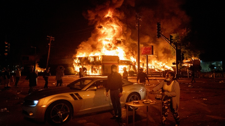 An AutoZone store burns as protesters gather outside of the Third Precinct in Minneapolis in the days after George Floyd s death in 2020.
