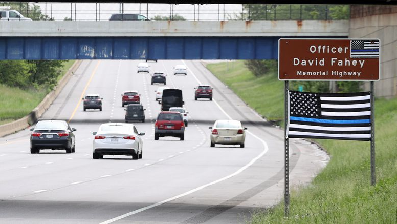 A Thin Blue Line flag hangs below the sign honoring fallen Cleveland Police Officer David Fahey, who was killed in the line of duty along this stretch of Interstate 90 in 2017.