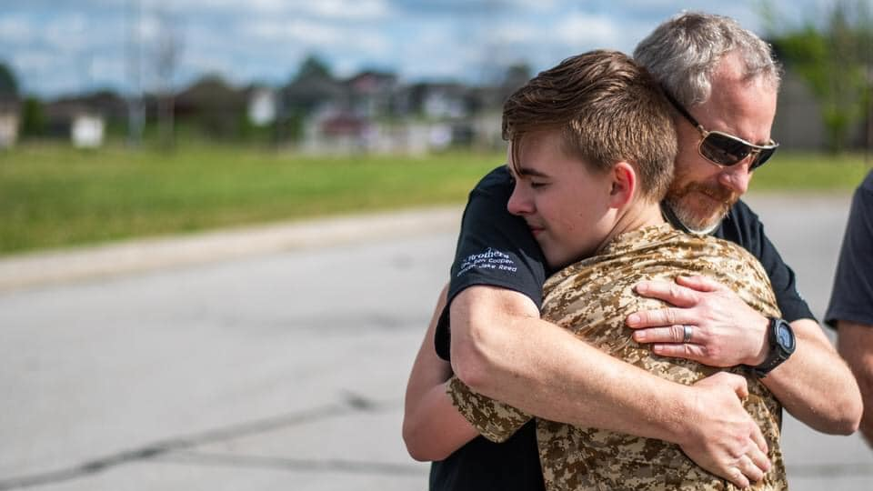 Joplin, MO, Police Officer Rick Hirshey, who was shot in the face in a March shooting that left two officers dead, hugs Zechariah of Running 4 Heroes Inc. during an event in May.