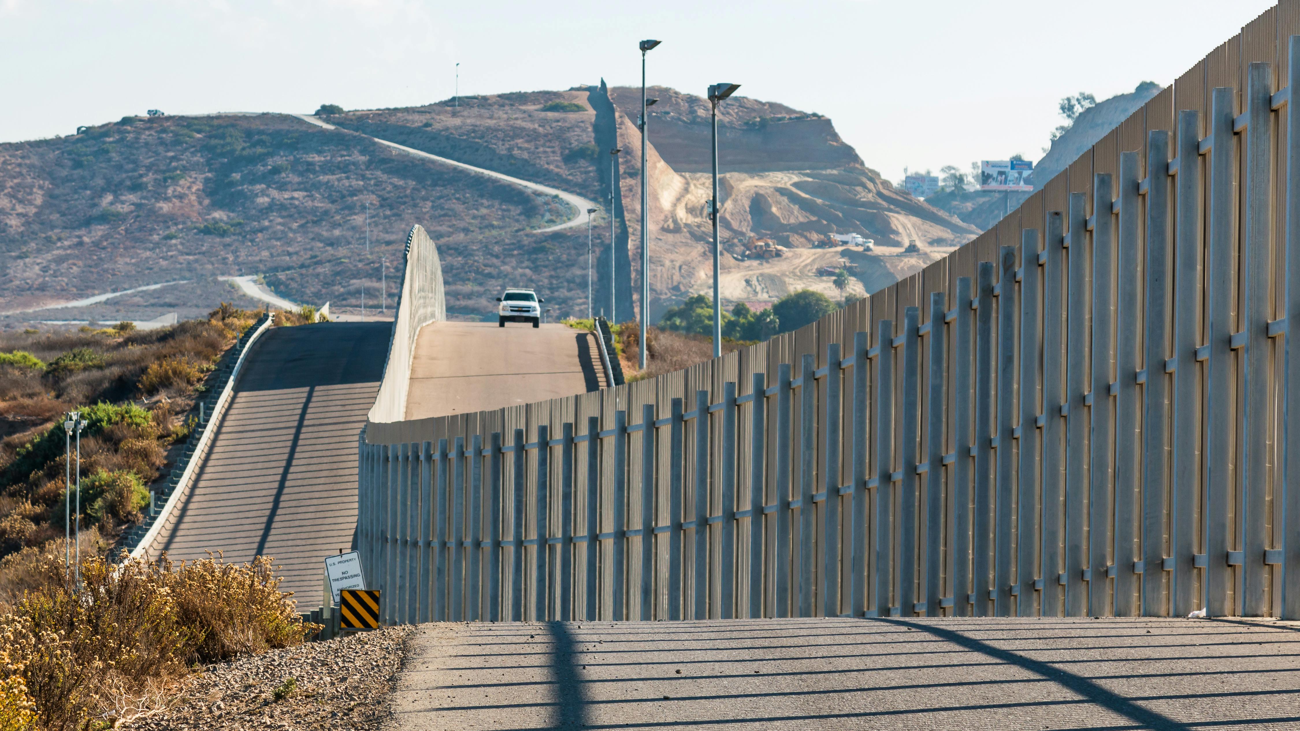 The international border wall between San Diego, California and Tijuana, Mexico, is seen with an approaching U.S. Border Patrol vehicle on a nearby hill.