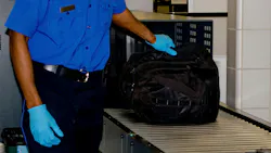 TSA worker scans an airport bag. TSA worker scans an airport bag.