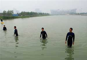 Frogmen wade out of the body of water after a security check near National Stadium, also known as Bird's Nest, background, in Beijing, Thursday, Aug. 7, 2008, a day before the opening ceremony of the Beijing 2008 Olympics.
