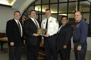 (l-r) Kevin Lehan (EM24), Sam Splaine (Splaine Security Systems), CJPVFD Chief James Seavey, Bernie Ramos (EM24) and CJPVFD Vice President David Cohen pose together with a plaque that commemorates the Responder Reward Donation.