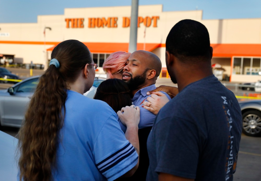 Home Depot employees comfort one another outside the Dallas store after two officers and a civilian were shot by a man on Tuesday, April 24, 2018.