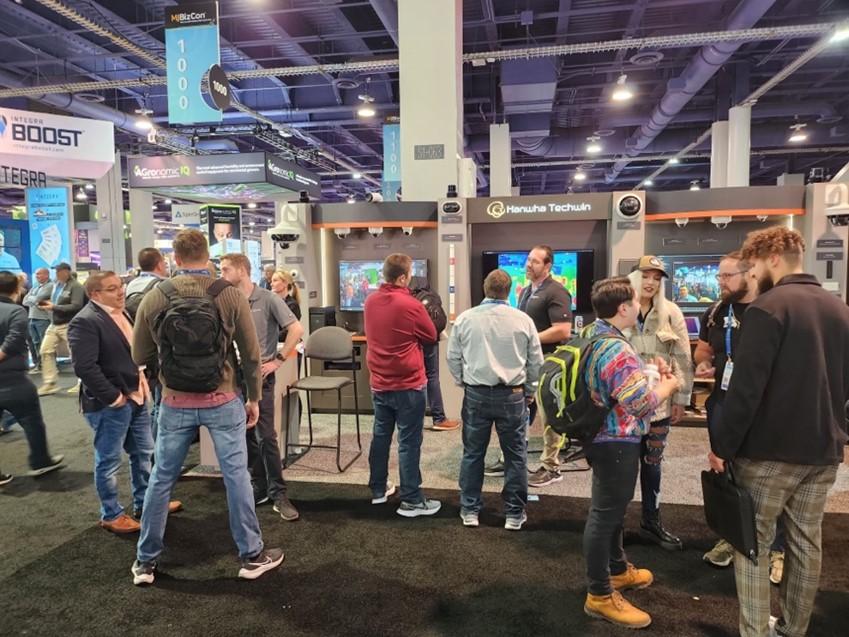 A crowd of interested attendees gathers at the Hanwha Vision booth.