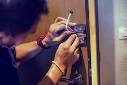 A service tech works on a digital door lock security system. A service tech works on a digital door lock security system.