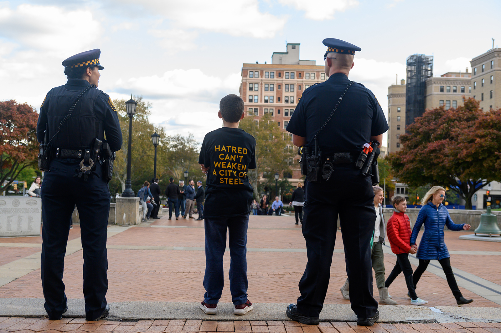 Sam Goldston, 13, stands with 2 Pittsburgh City Police as attendees gather for a public memorial service honoring the lives lost in the attack on the Tree of Life Synagogue on Oct. 27, 2018, at the Soldiers and Sailors Memorial on Oct. 27, 2019 in Pittsburgh, Pennsylvania. One year ago, Robert Bowers killed 11 people and wounded several others during an attack of the Tree of Life synagogue.