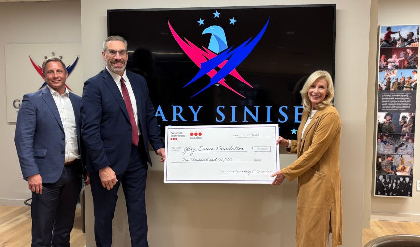 Securitas Technology team members present a donation check to the Gary Sinise Foundation, reflecting attendee engagement generated at the company&rsquo;s GSX 2025 booth.